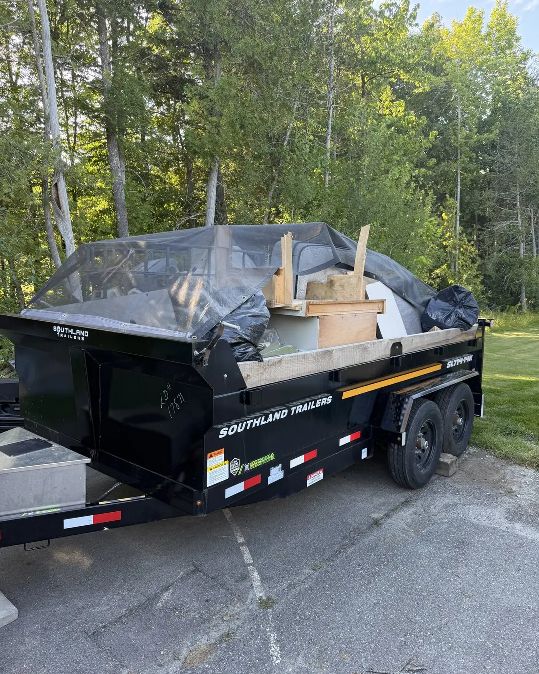 Loaded trailer on a driveway with trees behind it